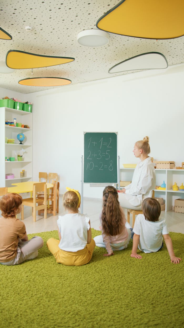 Children sitting in a colorful classroom learning basic math from a teacher.
